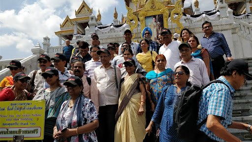 Travellers gathered on the steps of a golden temple in Thailand, one of many memorable group journeys.