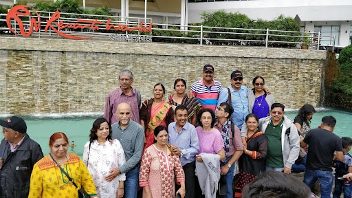 A cheerful group posing beside a waterfall fountain during a comfortable sightseeing stop.